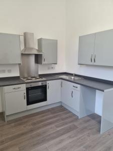 an empty kitchen with white cabinets and a sink at Park View in Hull