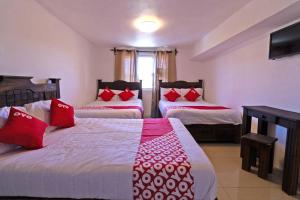 a hotel room with two beds with red pillows at OYO Hotel Punta Guadalupe, San Cristóbal de las Casas in San Cristóbal de Las Casas
