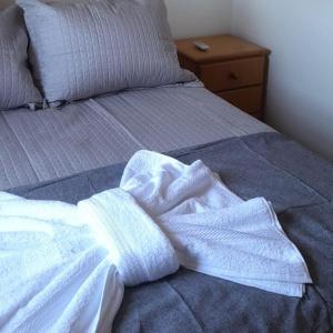 uma cama não feita com lençóis brancos e uma mesa de cabeceira em Casa ampla com lareira e churrasqueira em Canela