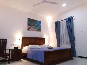 a bedroom with a bed with blue sheets and a ceiling fan at Villa Talpe in Talpe