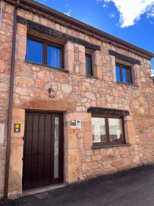 um edifício de tijolos com uma porta e três janelas em Casa Rural La Colmena em Condemios de Abajo