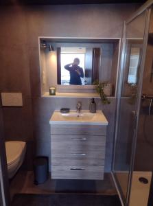 un homme prenant une photo dans un miroir de salle de bains dans l'établissement VOTRE HORIZON, à Aywaille