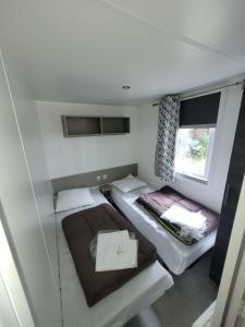 een kleine kamer met 2 bedden en een raam bij mobil home - camping les dunes de Contis in Saint-Julien-en-Born