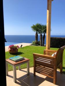 eine Bank und einen Tisch mit Meerblick in der Unterkunft Morning Star Villa in Arco da Calheta