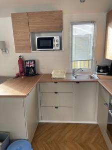 a small kitchen with a sink and a microwave at Mobilhome Sables du midi in Valras-Plage