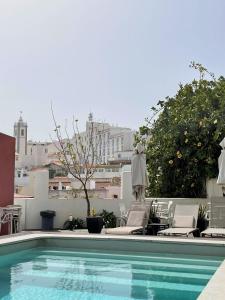 a swimming pool with chaises and chairs on a building at Fisherman's Albufeira Cosy Studio in Albufeira