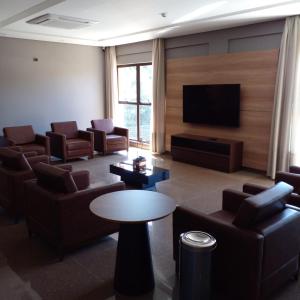 uma sala de estar com sofás e uma televisão de ecrã plano em Hotelog Tibagi em Ponta Grossa