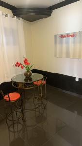 uma mesa com cadeiras e um vaso com flores em Versat Motel em Barretos