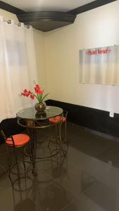 een tafel met stoelen en een vaas met bloemen erop bij Versat Motel in Barretos
