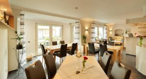 a restaurant with tables and chairs and a kitchen at Gästehaus Alexanderhof in Leiwen