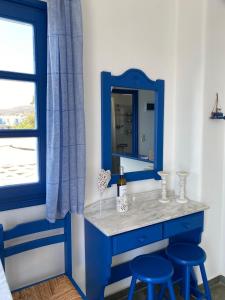 a blue vanity with two stools and a mirror at Cavos Studio by the sea (West) in Drios