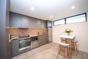 a kitchen with gray cabinets and a table and chairs at Brookside Central Wanaka Luxury Apartment in Wanaka