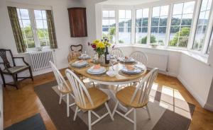 a dining room with a table and chairs and windows at Pipiriki - Spectacular views and outstanding garden in peaceful location in Dittisham