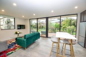 ein Wohnzimmer mit einem grünen Sofa und einem Tisch in der Unterkunft Brookside Central Wanaka Luxury Apartment in Wanaka