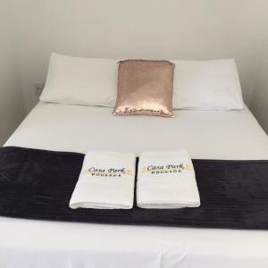 uma cama branca com duas almofadas em cima em Pousada CasaPark em Penha