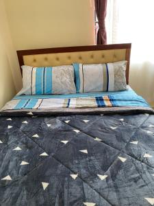 a bed with a blue quilt and pillows on it at Joshua’s place: cosy furnished one bedroom apt in Meru