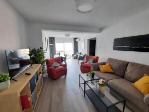 ein Wohnzimmer mit einem Sofa und roten Stühlen in der Unterkunft Balcón Victoria in Málaga