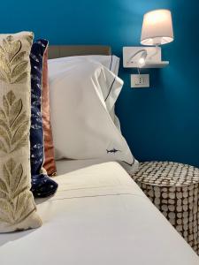 Una cama blanca con almohadas y una lámpara en una pared azul. en L'EMPORIO ROOMS, en Manarola