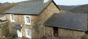 an old stone house with a black roof at CASA DA POUPARIÑA in Deveso