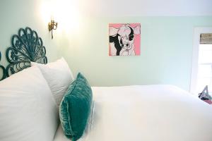 ein Bett mit weißen Kissen und ein Bild einer Kuh in der Unterkunft The Frenchie in Round Top