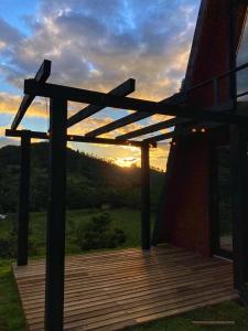 a wooden deck with a sunset in the background at Morada do Corujão - Aconchego in Praia Grande