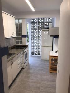 une cuisine avec des armoires blanches et un réfrigérateur blanc dans l'établissement Apartamento a 100m de la Cala Blanca, à Jávea
