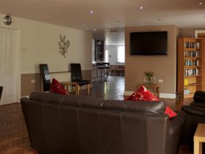 a living room with a leather couch and a television at The Liver View in Birkenhead