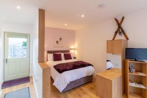 a bedroom with a bed and a television at Allt Mor Rentals - Chalet with hot tub, And Studio Apartment no hot tub in Roybridge