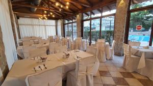 una sala de banquetes con mesas y sillas blancas en una habitación en ZAKROS HOTEL en Tolón