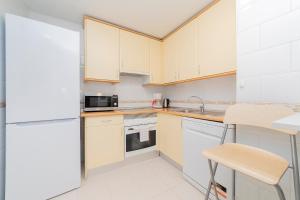 una cocina con armarios blancos y electrodomésticos blancos en ACACIAS en Madrid