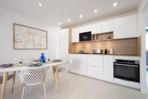 a kitchen with white cabinets and a table and chairs at SERRENDY 2-bedroom apartment near Croisette in Cannes