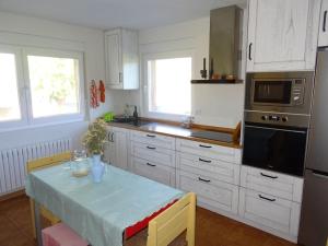 cocina blanca con mesa y microondas en Casela de Villalba- casa rural, en Vilalba