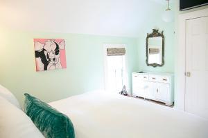 a bedroom with a white bed and a painting on the wall at The Frenchie in Round Top