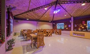 un restaurante con mesas y sillas de madera e iluminación púrpura en Treebo Trend Kaira Resort With Pool View 5 Km From Jim Corbett Jungle Safari en Rāmnagar
