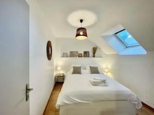 ein Schlafzimmer mit einem weißen Bett und einem Fenster in der Unterkunft Émeraude Lumineux T3 au cœur du village, à 5 min des plages in Saint-Méloir-des-Ondes