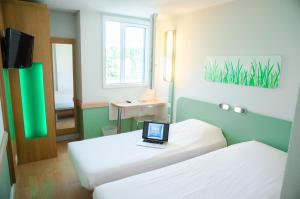 Zimmer mit 2 Betten und einem Laptop auf dem Schreibtisch in der Unterkunft ibis budget Aeroport le Bourget Garonor in Le Blanc-Mesnil