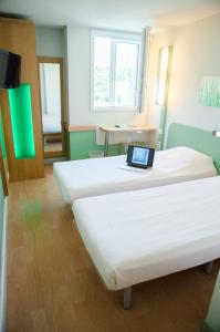 a room with two beds with a laptop on it at ibis budget Aeroport le Bourget Garonor in Le Blanc-Mesnil