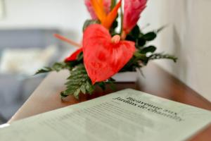 un libro seduto su un tavolo con un vaso di fiori di Les jardins de CHANTILLY -Bungalows 4 étoiles avec jardins et piscines privées a Baie-Mahault