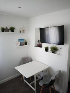 a white table with two chairs and a tv on a wall at Gemütliche 1 Zimmer Ferienwohnung in Ludwigsburg