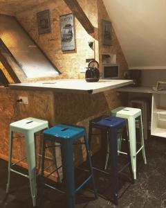 une cuisine avec trois tabourets bleus devant un comptoir dans l'établissement Hameau des deux ailes, à Précigné