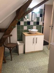 ein Badezimmer mit einem Waschbecken und einem Stuhl im Dachgeschoss in der Unterkunft Hameau des deux ailes in Précigné