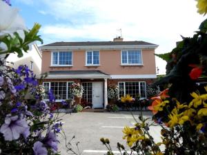 una casa rosa con flores delante en Cillcearn House, en Killarney