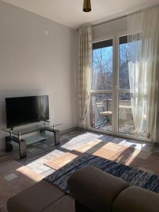 a living room with a tv and a large window at Apartmani Vila in Cetinje