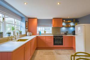 een keuken met oranje kasten en een witte koelkast bij Wheelwrights Cottage by Bloom Stays in Staple Cross