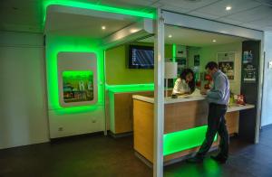 a man standing at a green bar in a restaurant at ibis budget Aeroport le Bourget Garonor in Le Blanc-Mesnil