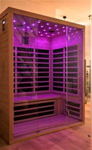 Habitación con iluminación púrpura en una pared de cristal en F2 avec sauna, vue d'exception place de la mairie, en Beauvais