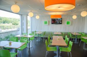 un comedor con mesas y sillas verdes en ibis budget Aeroport le Bourget Garonor, en Le Blanc-Mesnil