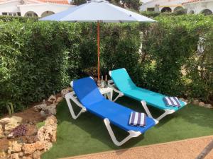 two blue and white chairs and an umbrella at FONOLL MARÍ in Cala en Forcat