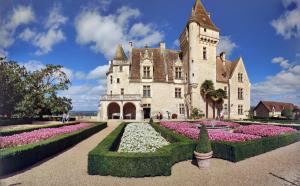 a castle with a garden of flowers in front of it at Villa Padam in Monsac
