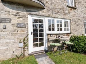 a table and chairs in front of a stone building at Slate Cottage in Helland